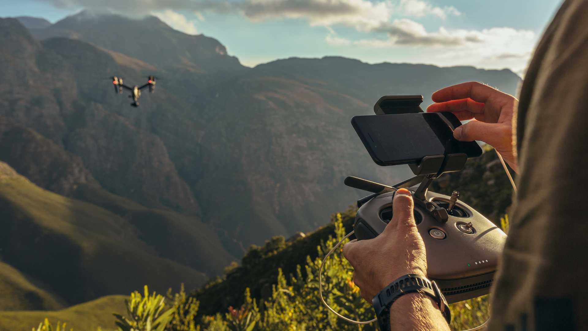 Remote controlling drone flying over the hills